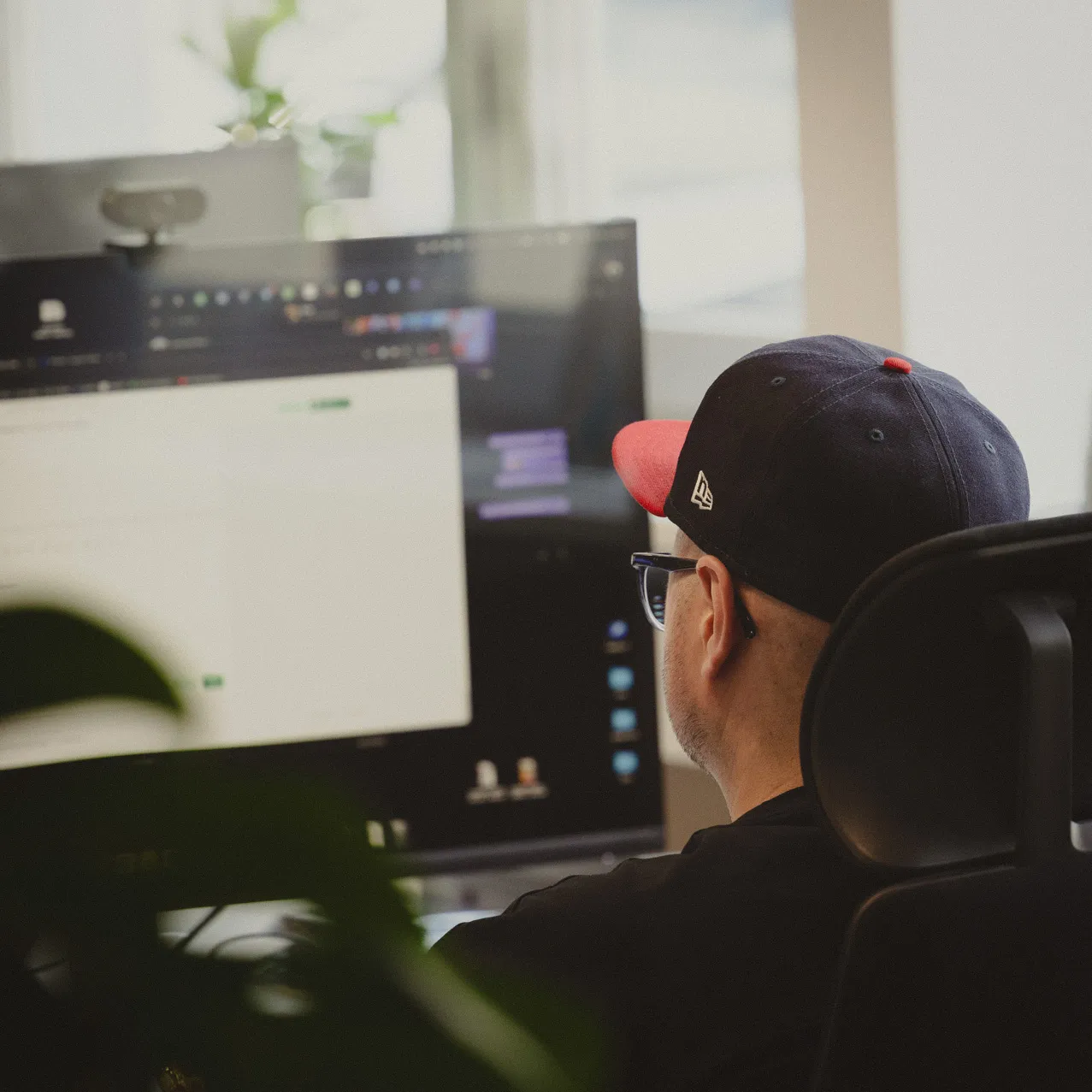 Another employee sitting at his desk in front of his computer working photographed from behind
